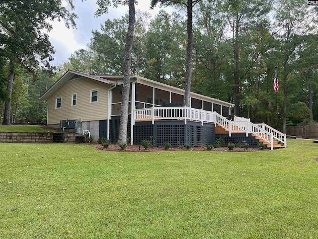 rear view of house featuring a wooden deck, a sunroom, and a yard