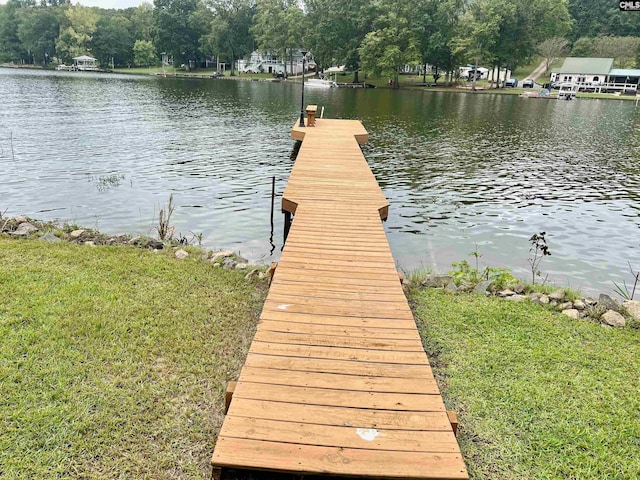 view of dock with a lawn and a water view