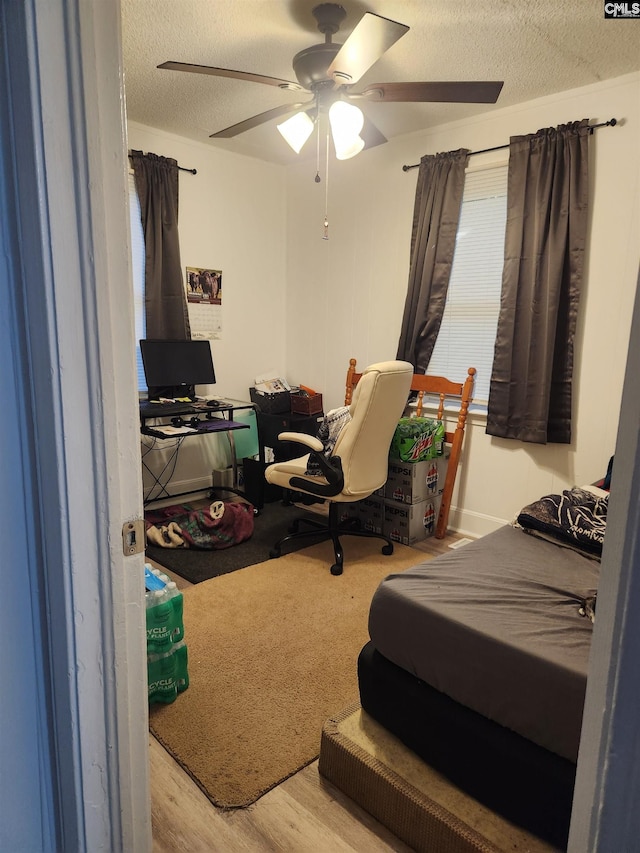 bedroom with ceiling fan, light wood-type flooring, and a textured ceiling