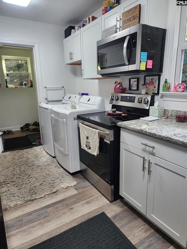 laundry room with separate washer and dryer, light hardwood / wood-style flooring, and a textured ceiling