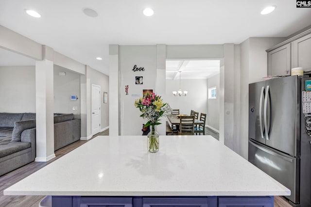 kitchen featuring stainless steel refrigerator, a chandelier, hardwood / wood-style floors, and a center island