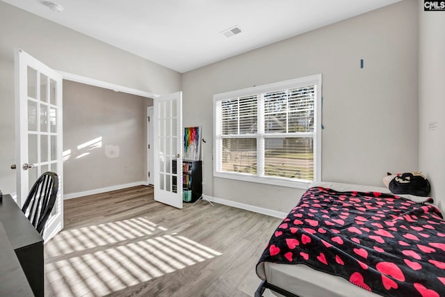 bedroom with light hardwood / wood-style floors and french doors