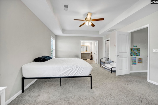 bedroom with carpet, ceiling fan, ensuite bathroom, and a raised ceiling