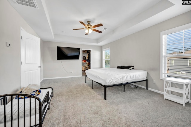 bedroom featuring carpet, a tray ceiling, and ceiling fan