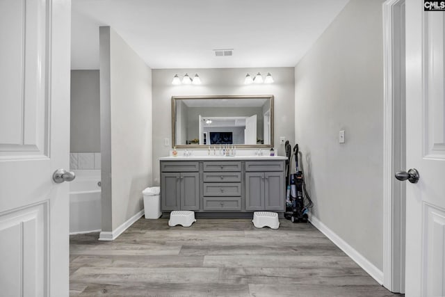 bathroom featuring vanity, a tub to relax in, and hardwood / wood-style flooring