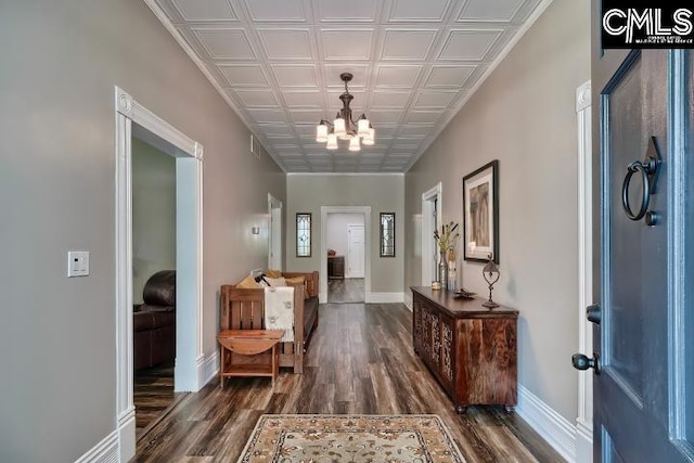 corridor with an inviting chandelier and dark hardwood / wood-style flooring