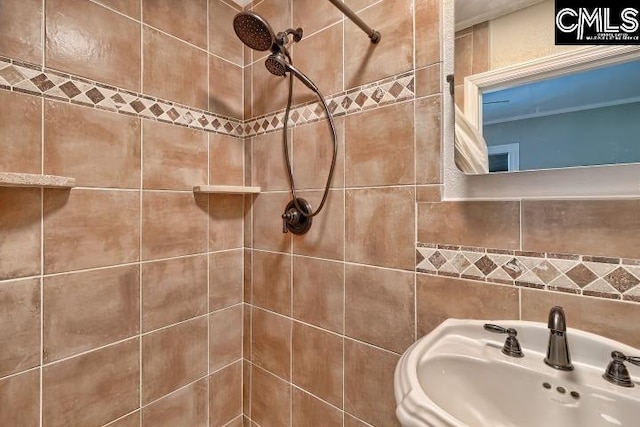 bathroom with tiled shower and sink