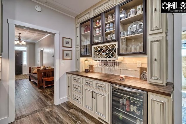 bar with wine cooler, a chandelier, dark hardwood / wood-style floors, crown molding, and butcher block counters