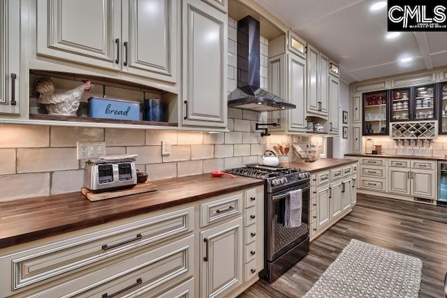 kitchen with gas stove, wood counters, dark wood-type flooring, tasteful backsplash, and wall chimney range hood