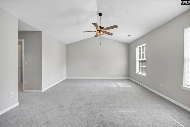 unfurnished room with a healthy amount of sunlight, carpet flooring, vaulted ceiling, and ceiling fan