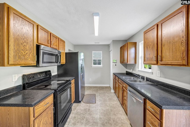 kitchen with stainless steel appliances, light tile patterned flooring, a healthy amount of sunlight, and sink