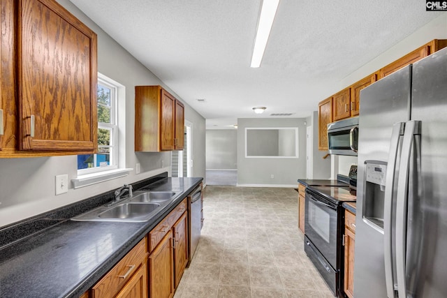 kitchen with appliances with stainless steel finishes, a textured ceiling, and sink