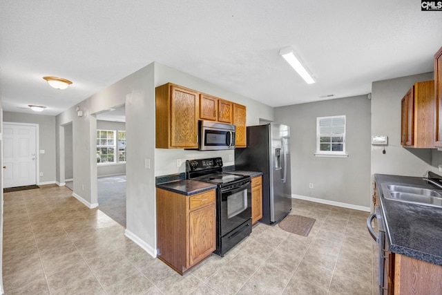 kitchen with stainless steel appliances, a textured ceiling, light tile patterned flooring, and sink