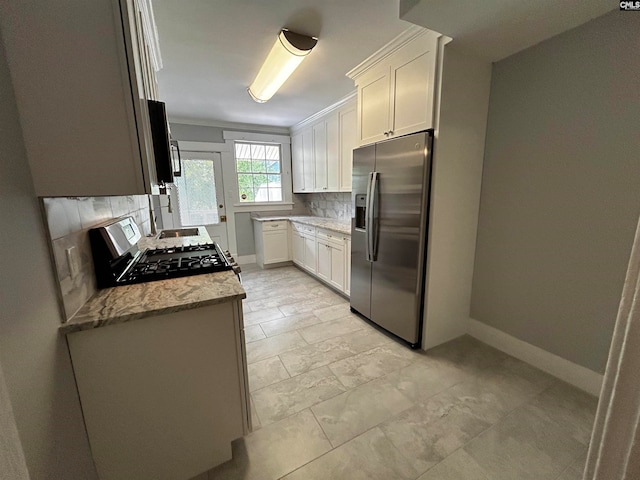 kitchen with light stone counters, stainless steel appliances, tasteful backsplash, and white cabinetry