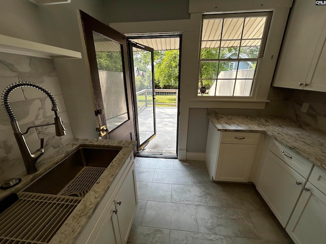 kitchen featuring white cabinets, light stone countertops, sink, and decorative backsplash