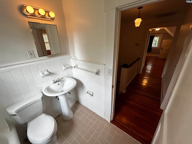 bathroom featuring hardwood / wood-style flooring, tile walls, and toilet