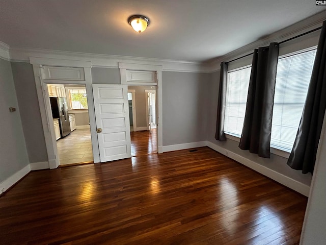 unfurnished bedroom featuring ornamental molding, stainless steel refrigerator with ice dispenser, and dark wood-type flooring