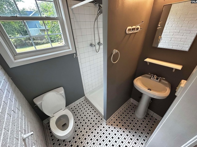 bathroom featuring a tile shower, tile patterned floors, and toilet