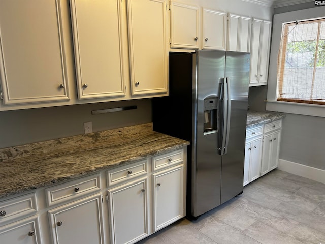 kitchen featuring dark stone countertops, white cabinets, crown molding, and stainless steel fridge