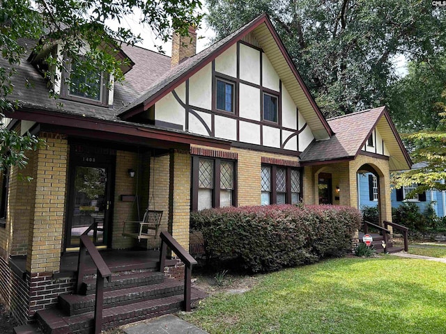 tudor house featuring a front yard and covered porch