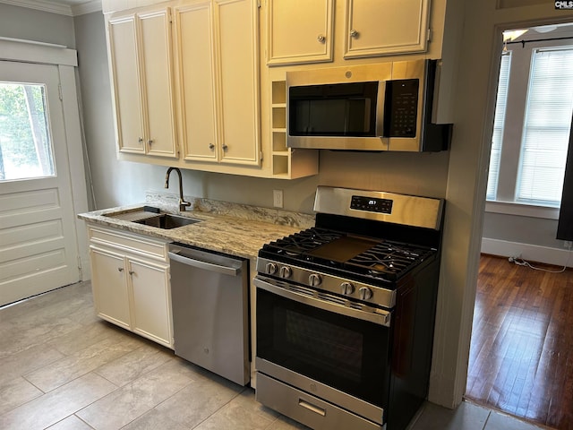 kitchen featuring sink, ornamental molding, light hardwood / wood-style flooring, stainless steel appliances, and light stone countertops