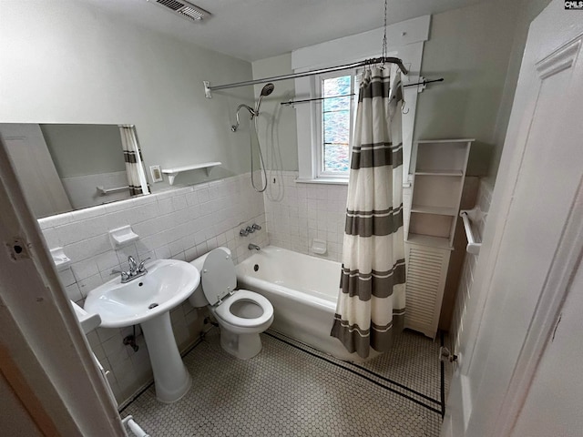 bathroom with tile walls, tile patterned flooring, shower / bathtub combination with curtain, and toilet