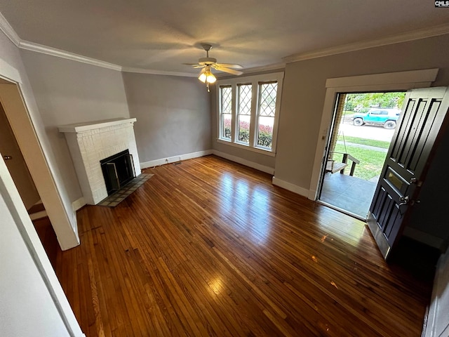 unfurnished living room with crown molding, dark hardwood / wood-style flooring, ceiling fan, and a brick fireplace