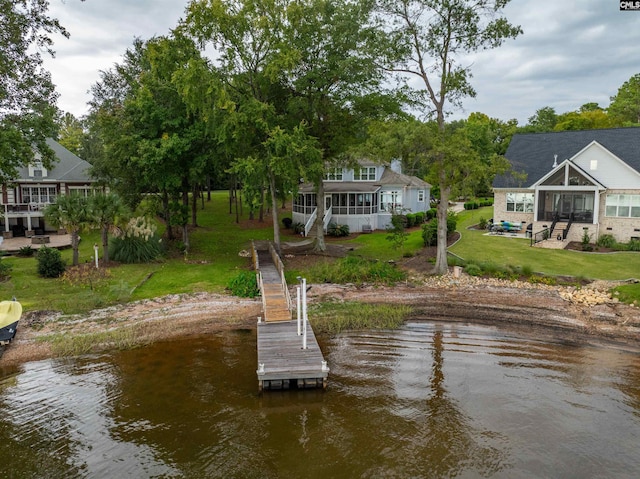 view of dock with a lawn and a water view