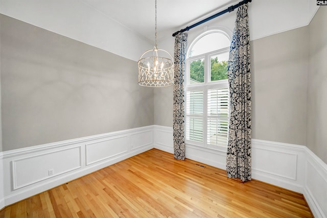 empty room featuring a notable chandelier and wood-type flooring