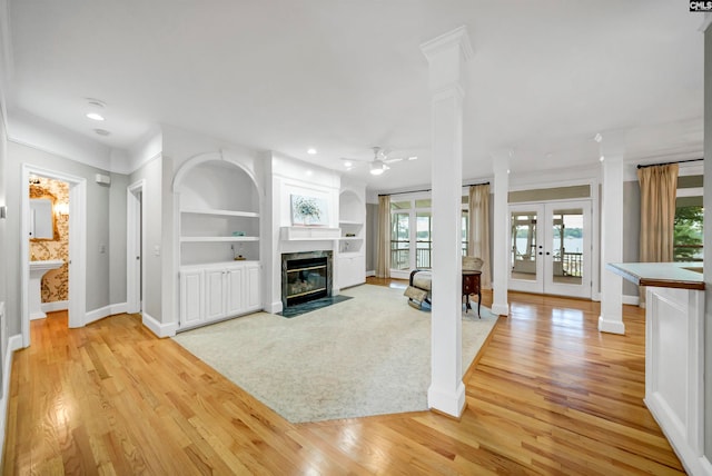 unfurnished living room with light hardwood / wood-style floors, a fireplace, ceiling fan, french doors, and a healthy amount of sunlight