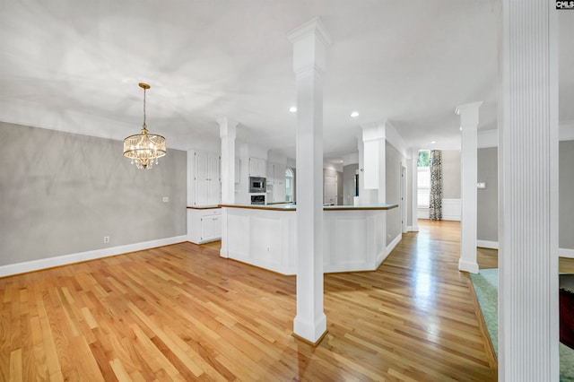 kitchen featuring decorative columns, white cabinetry, and light hardwood / wood-style floors