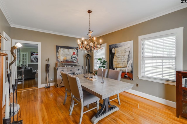 dining room with a healthy amount of sunlight, light hardwood / wood-style floors, crown molding, and a chandelier