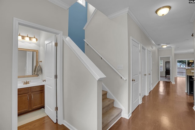 stairs featuring wood-type flooring, sink, and ornamental molding