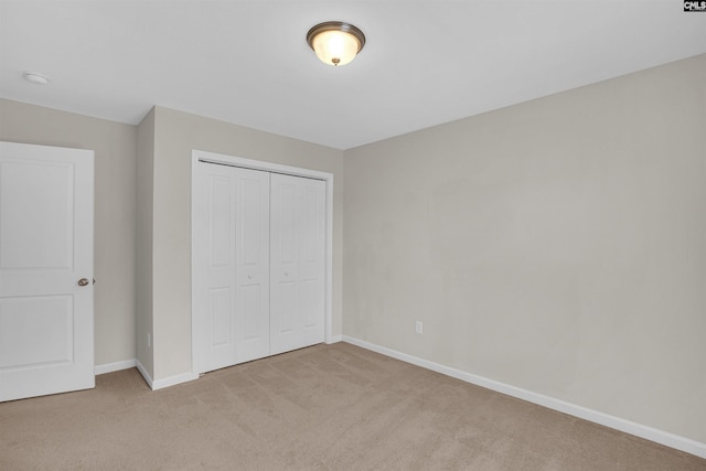 unfurnished bedroom with light carpet and a closet