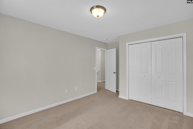 unfurnished bedroom with light carpet and a closet