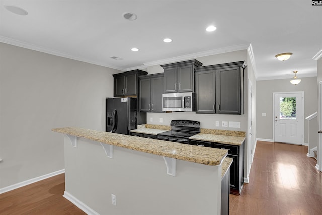 kitchen with ornamental molding, a kitchen island, black appliances, a breakfast bar area, and dark hardwood / wood-style flooring