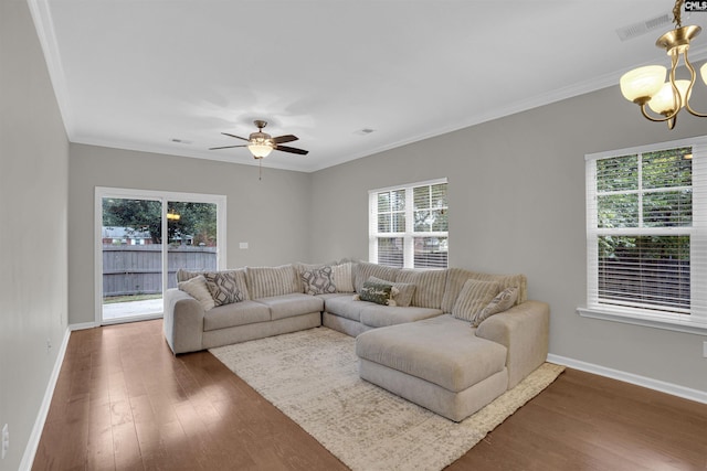 living room with ceiling fan with notable chandelier, crown molding, dark wood-type flooring, and a healthy amount of sunlight