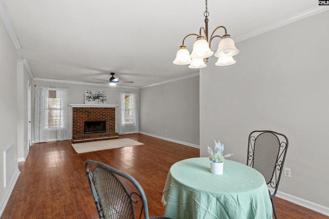 dining room featuring ceiling fan with notable chandelier, a brick fireplace, plenty of natural light, and dark hardwood / wood-style flooring