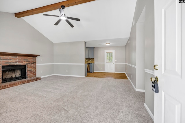 unfurnished living room with a brick fireplace, vaulted ceiling with beams, ceiling fan, and light colored carpet