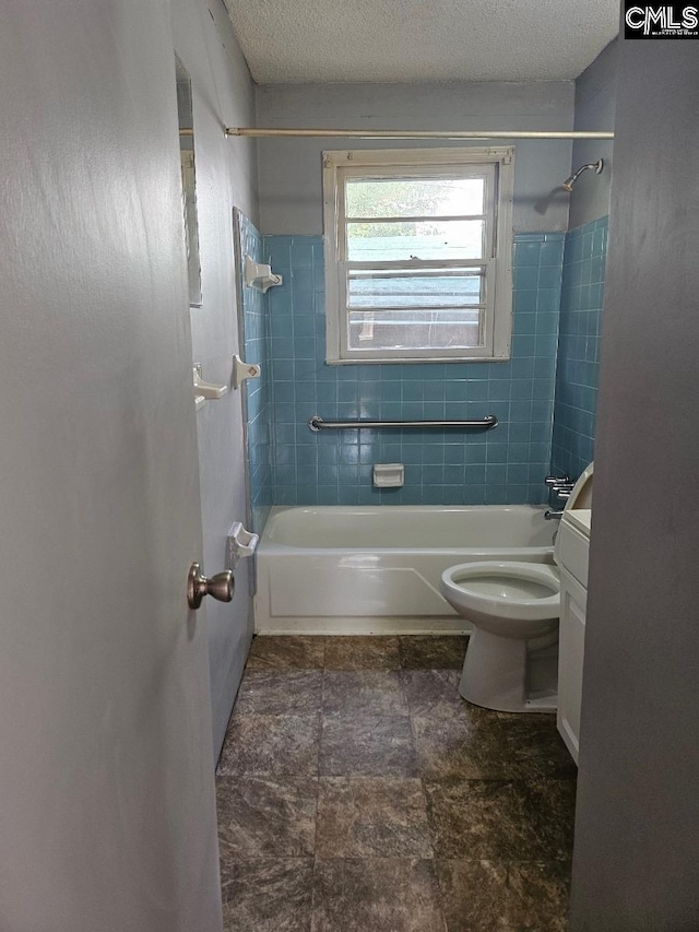 full bathroom featuring a textured ceiling, tiled shower / bath combo, vanity, and toilet