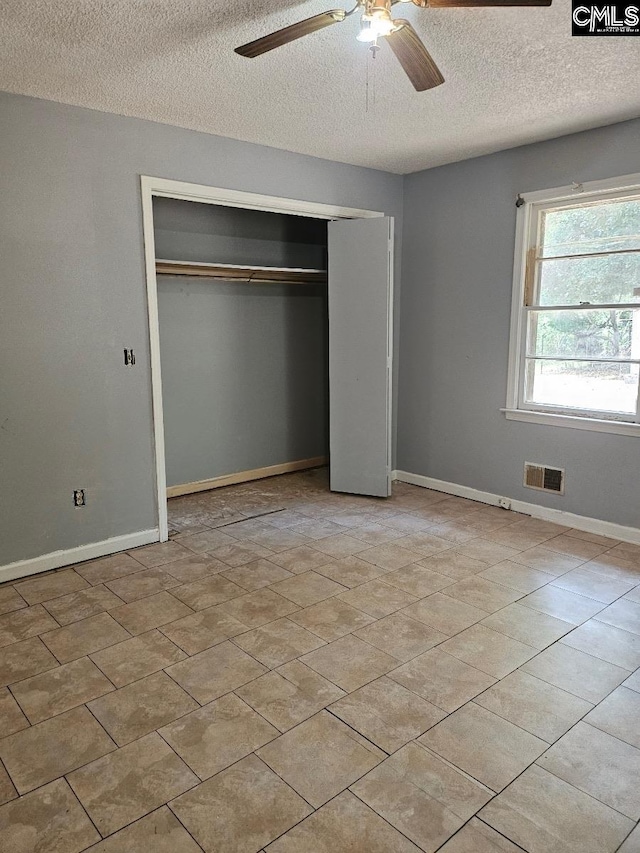 unfurnished bedroom with a textured ceiling, ceiling fan, and a closet