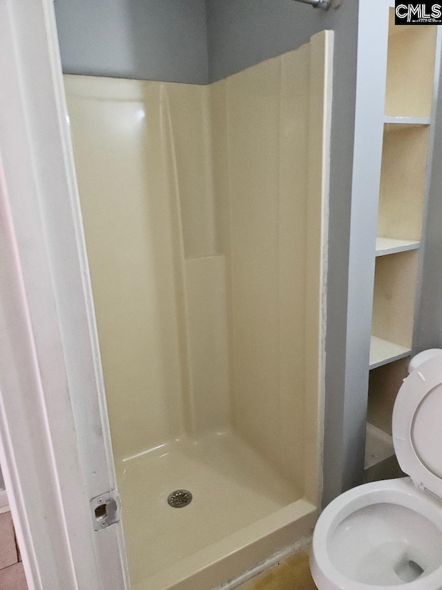 bathroom featuring walk in shower, tile patterned flooring, and toilet