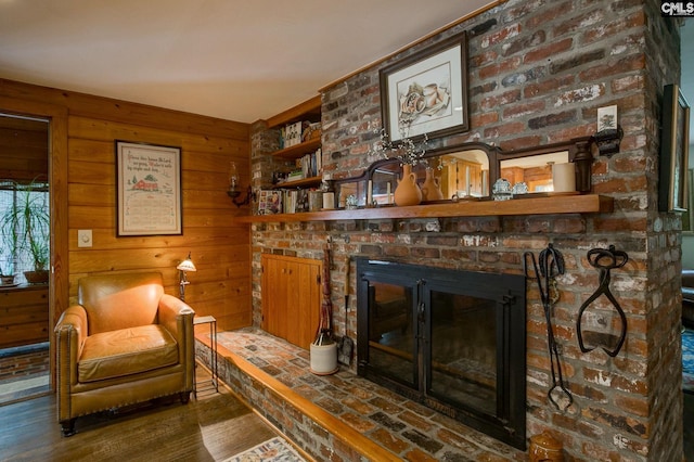 living room with a brick fireplace, wood walls, and hardwood / wood-style floors