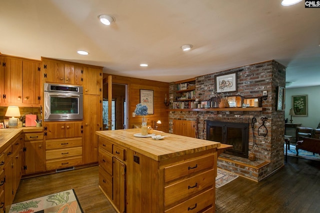 kitchen with a fireplace, a kitchen island, butcher block countertops, dark hardwood / wood-style flooring, and oven