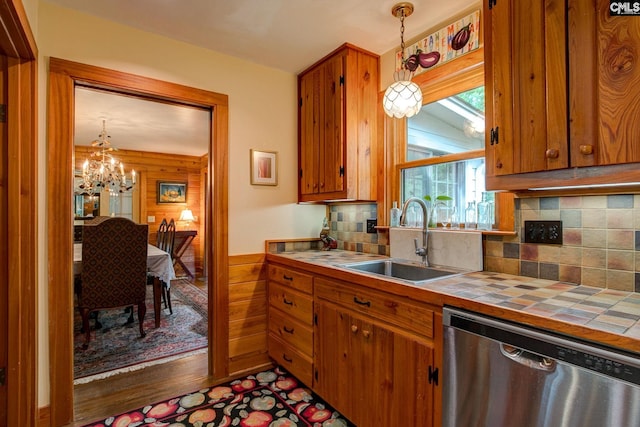 kitchen featuring hanging light fixtures, stainless steel dishwasher, backsplash, and sink