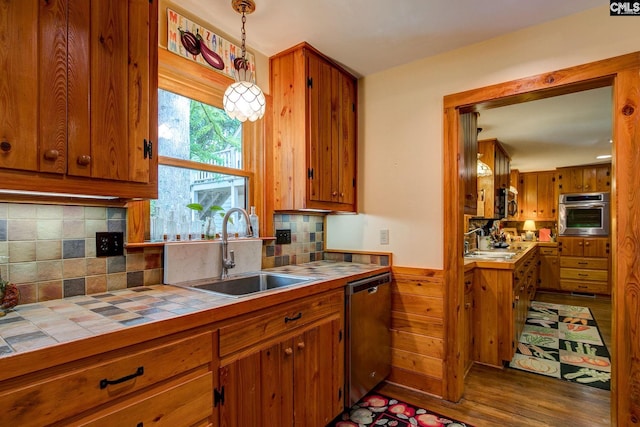 kitchen featuring hanging light fixtures, sink, hardwood / wood-style flooring, appliances with stainless steel finishes, and tile countertops