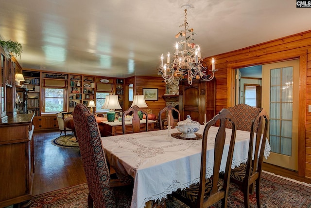 dining space with wood walls, dark hardwood / wood-style flooring, and a chandelier