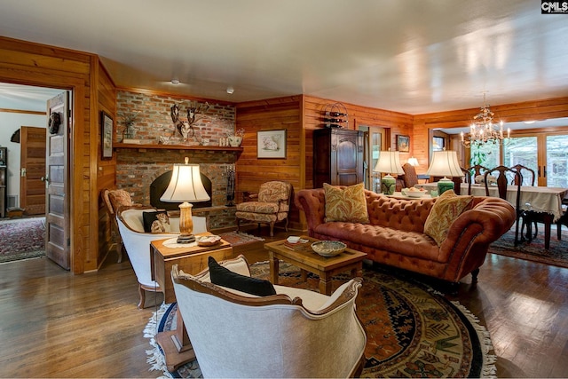 living room featuring a notable chandelier, wooden walls, a fireplace, and dark hardwood / wood-style flooring