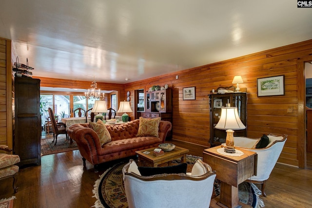 living room featuring wooden walls, dark hardwood / wood-style floors, and a chandelier