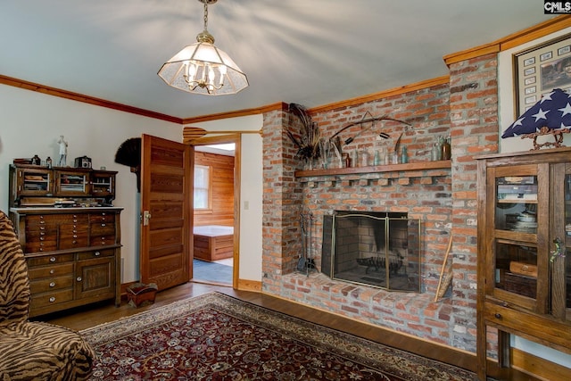 living room with a brick fireplace, wood-type flooring, a chandelier, and crown molding